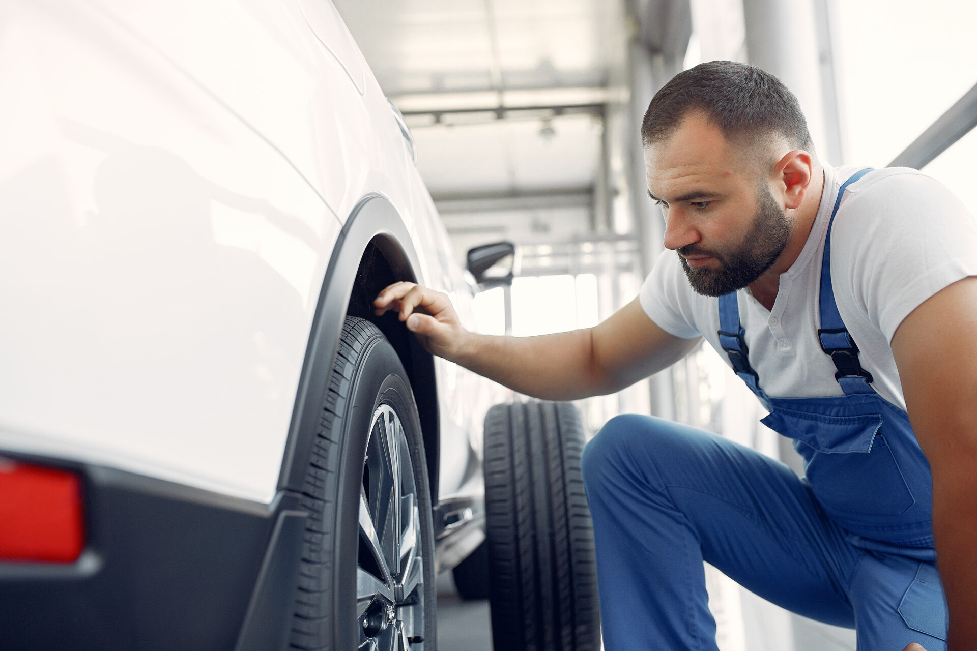 Wrker in a car salon. Expert checks the car. Man in a blue uniform.