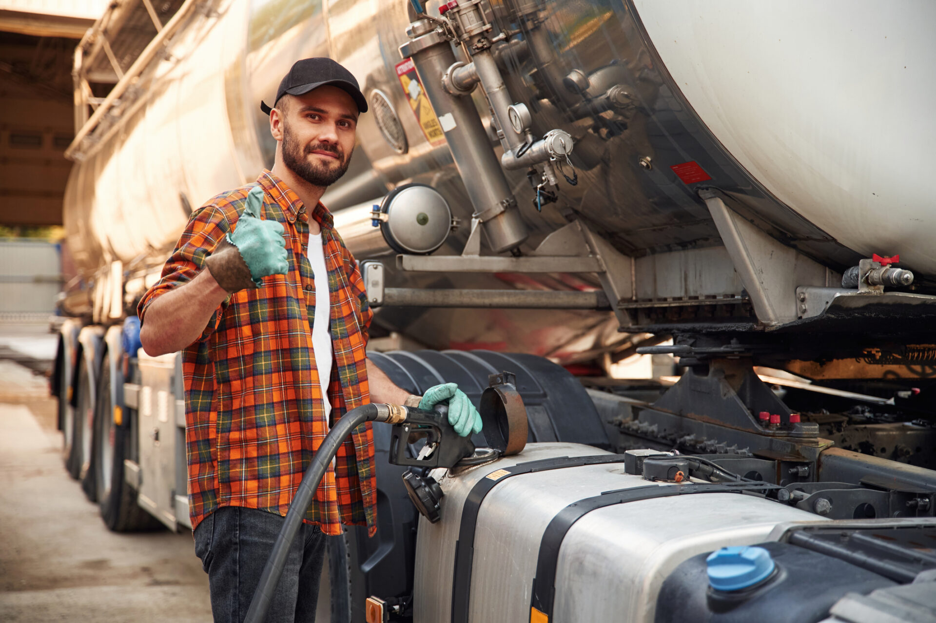 Young truck driver in casual clothes is refueling the vehicle.