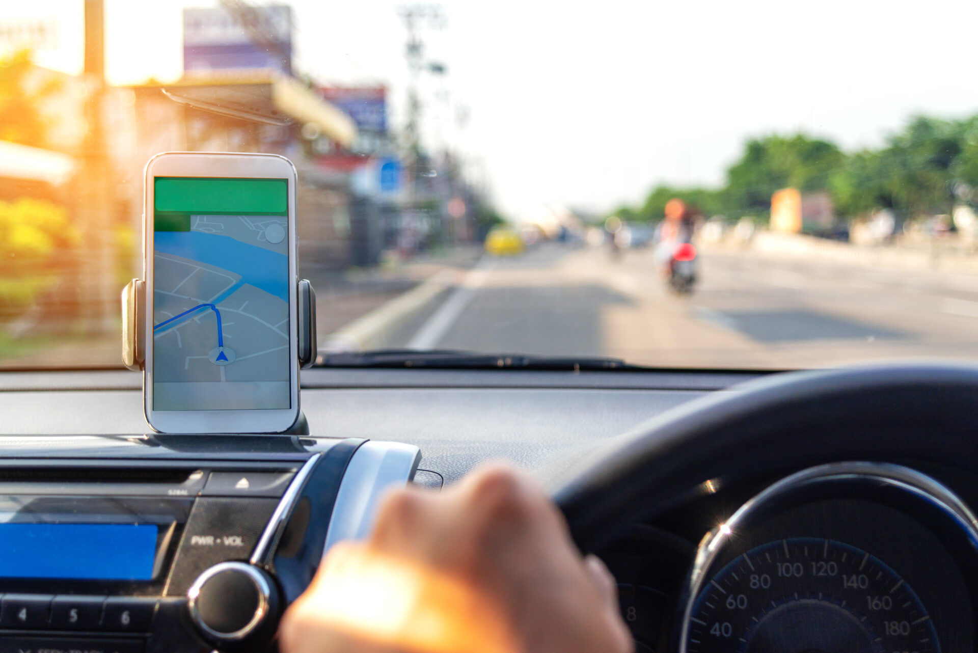 The map on the phone in the background of the dashboard and street . White mobile phone with map gps navigation fixed in the mounting. copy space.