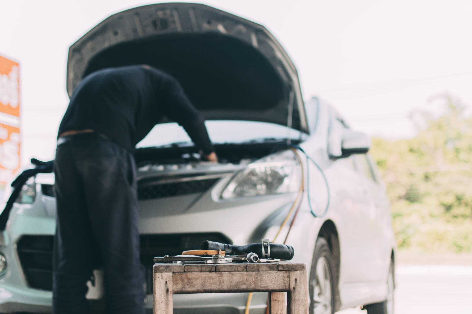 The mechanic is fixing the car in front of the car.