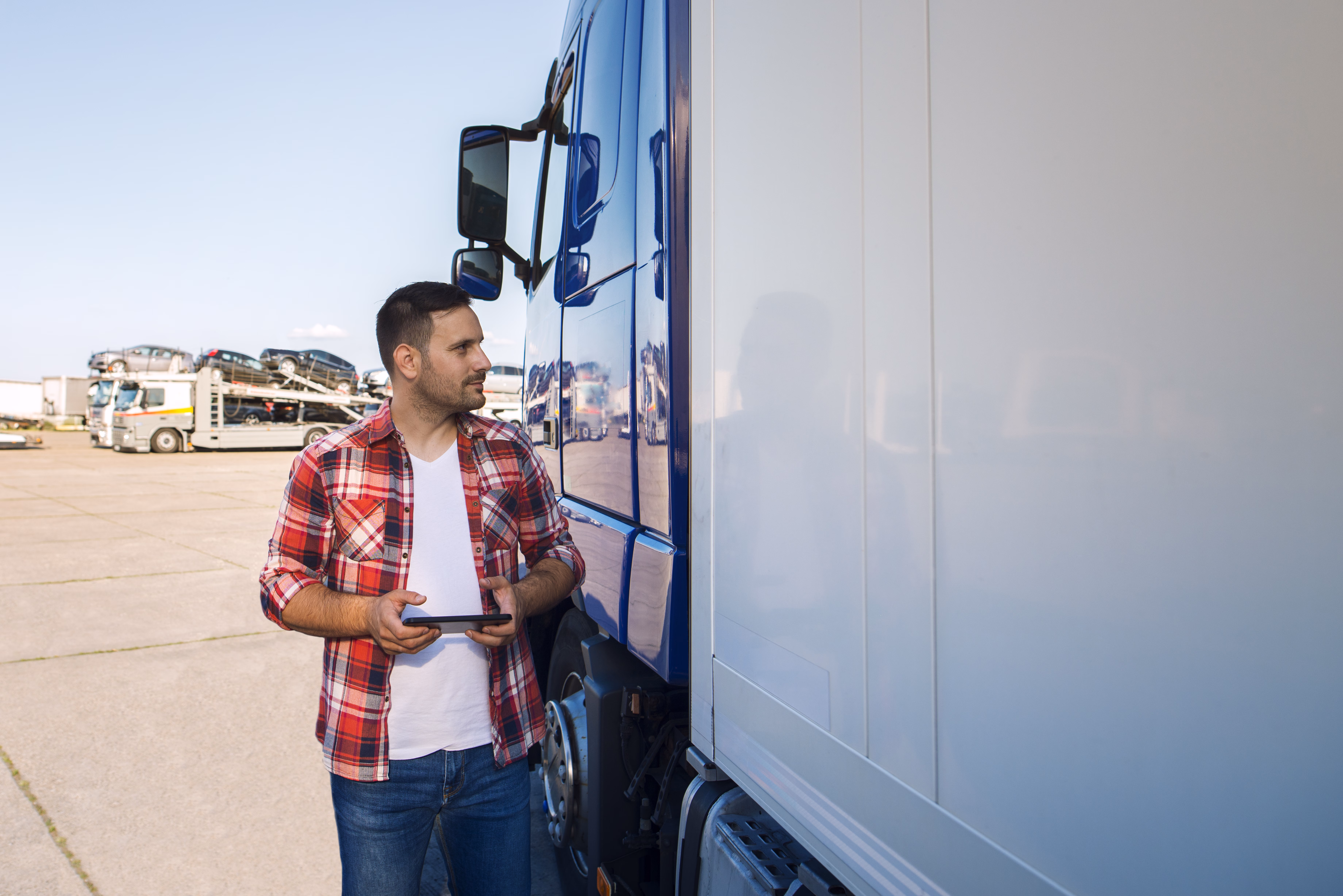 https://escortsensors.com/wp-content/uploads/2026/03/truck-driver-casual-clothes-standing-by-his-truck-with-tablet-looking-truck-jpg.avif