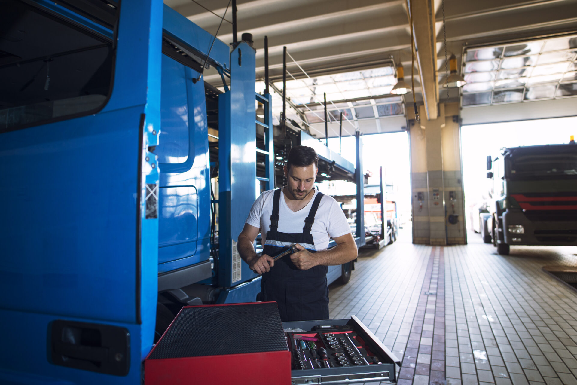 Truck mechanic servicing truck vehicle at workshop.